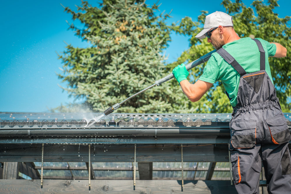 a man pressure cleaning house gutters