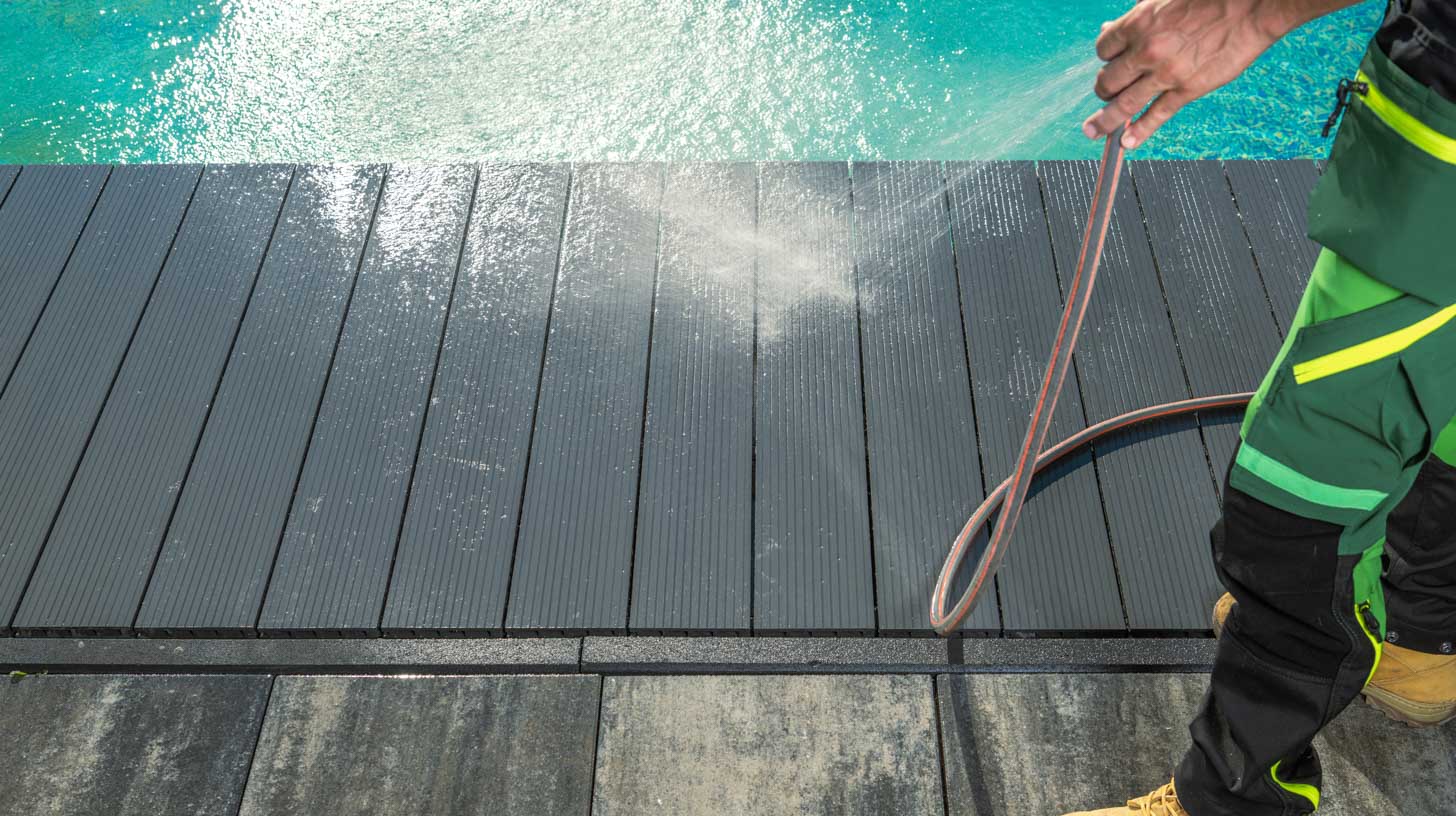 a man pressure cleaning a pool deck